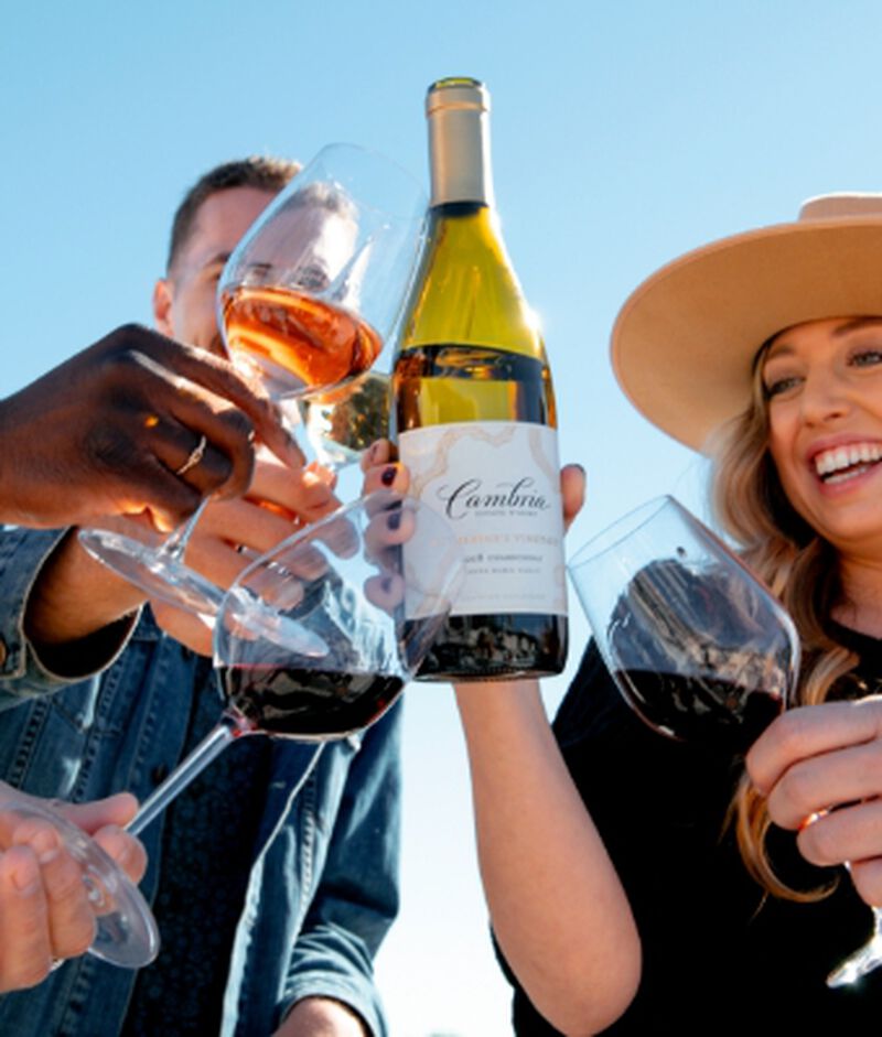 A group of friends toasting with a bottle of Cambria Katherine's Vineyard Chardonnay