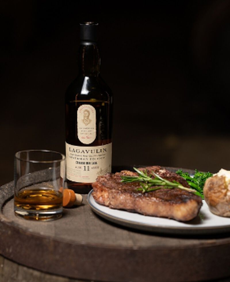 Bottle of Lagavulin Offerman Edition Charred Oak Cask 11 Year Old Islay Single Malt Scotch Whisky with a steak dinner