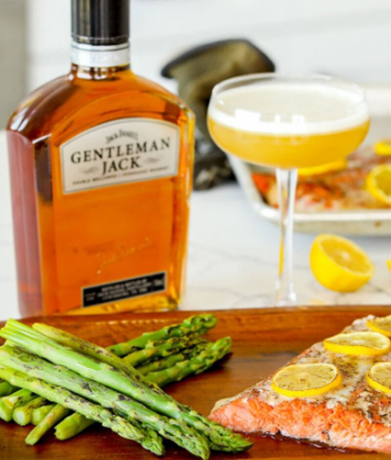 bottle of Jack Daniel's Gentleman Jack Tennessee Whiskey with a salmon dinner and cocktail