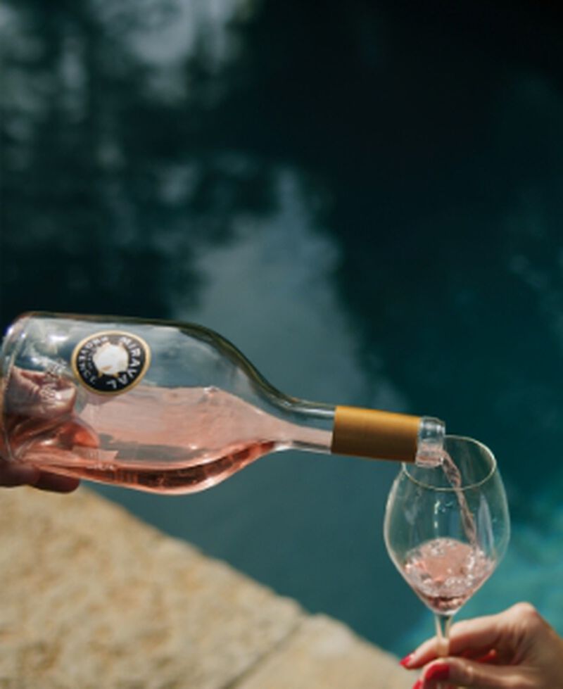 Bottle of Miraval Rosé being poured into a wine glass poolside