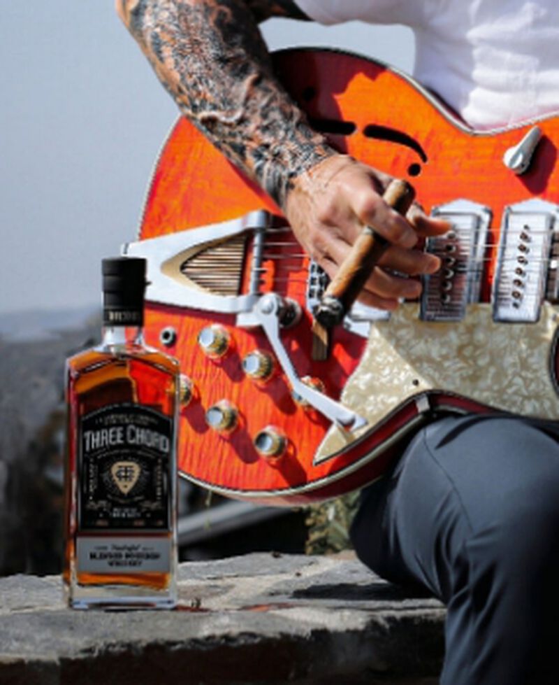 Three Chord Bourbon next to a guitar being played