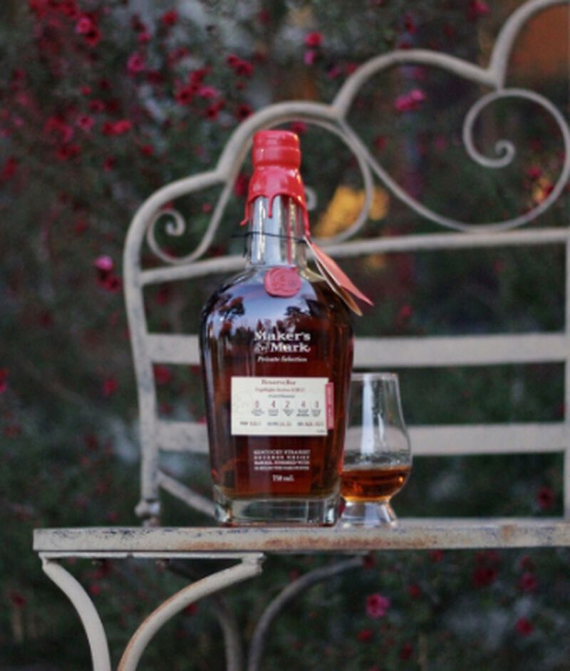 Bottle of Maker's Mark Private Selection Kentucky Bourbon Whisky S2B13 with a glass on a bench