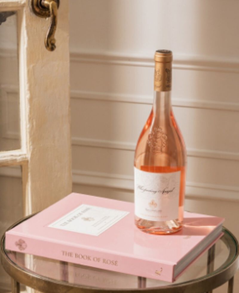 A bottle of Whispering Angel Rosé sitting on a pink book